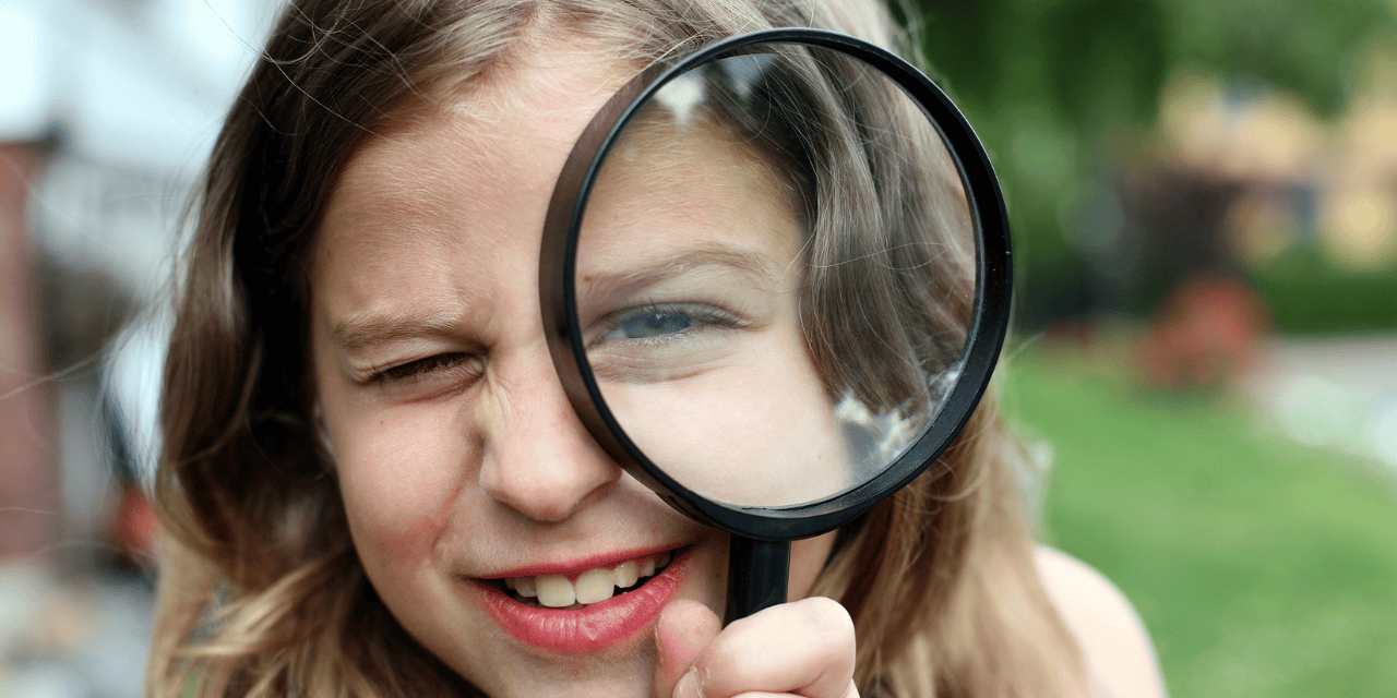 A kid dressed as a detective with a magnifying glass