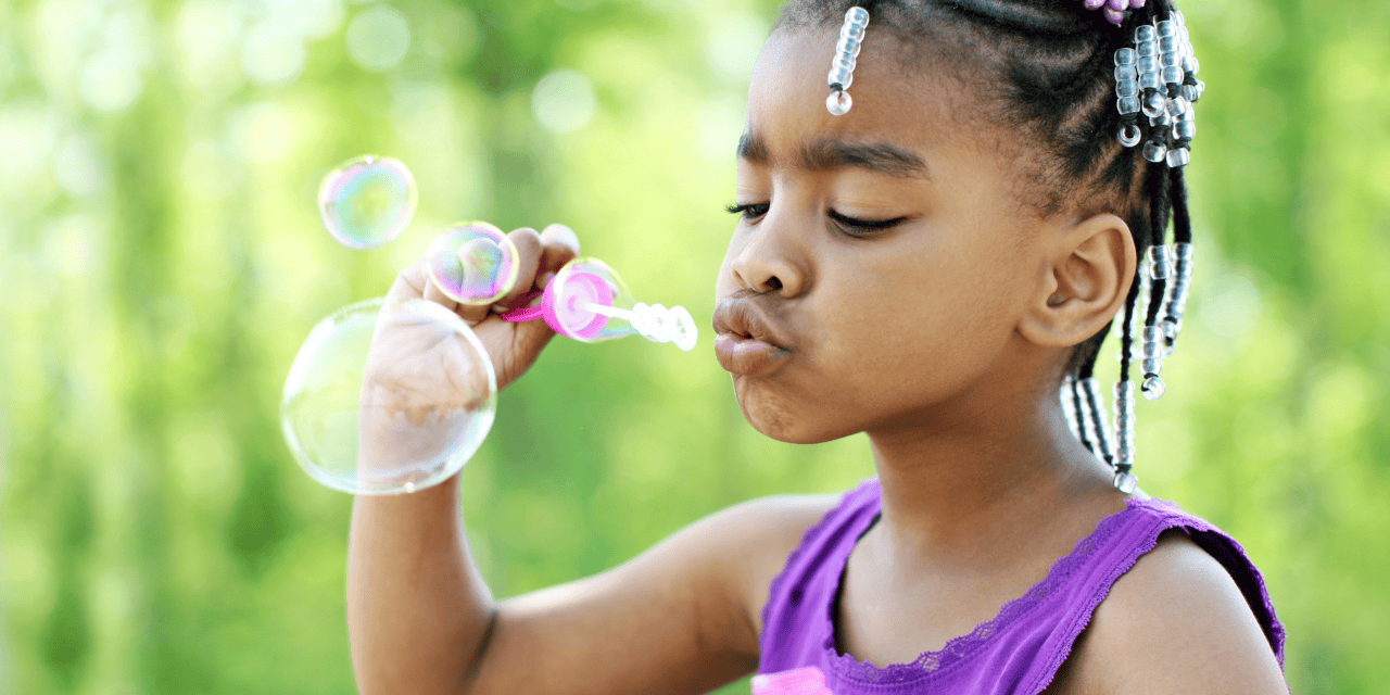 A young child happily blowing bubbles