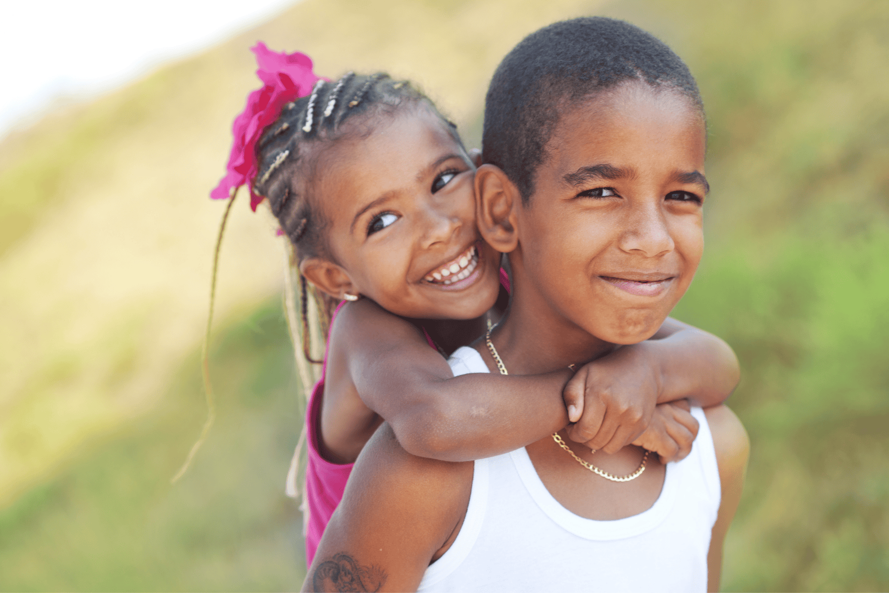 A sister and brother laughing together outdoors