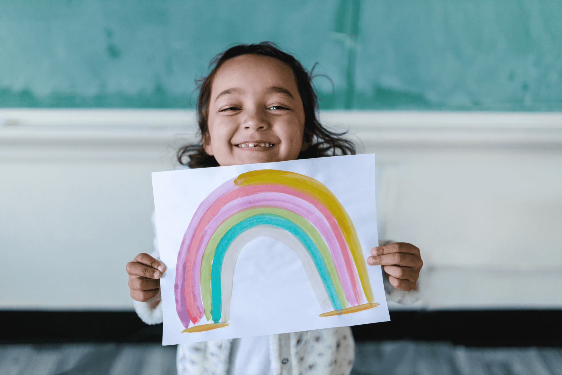 A child holding up a rainbow she painted