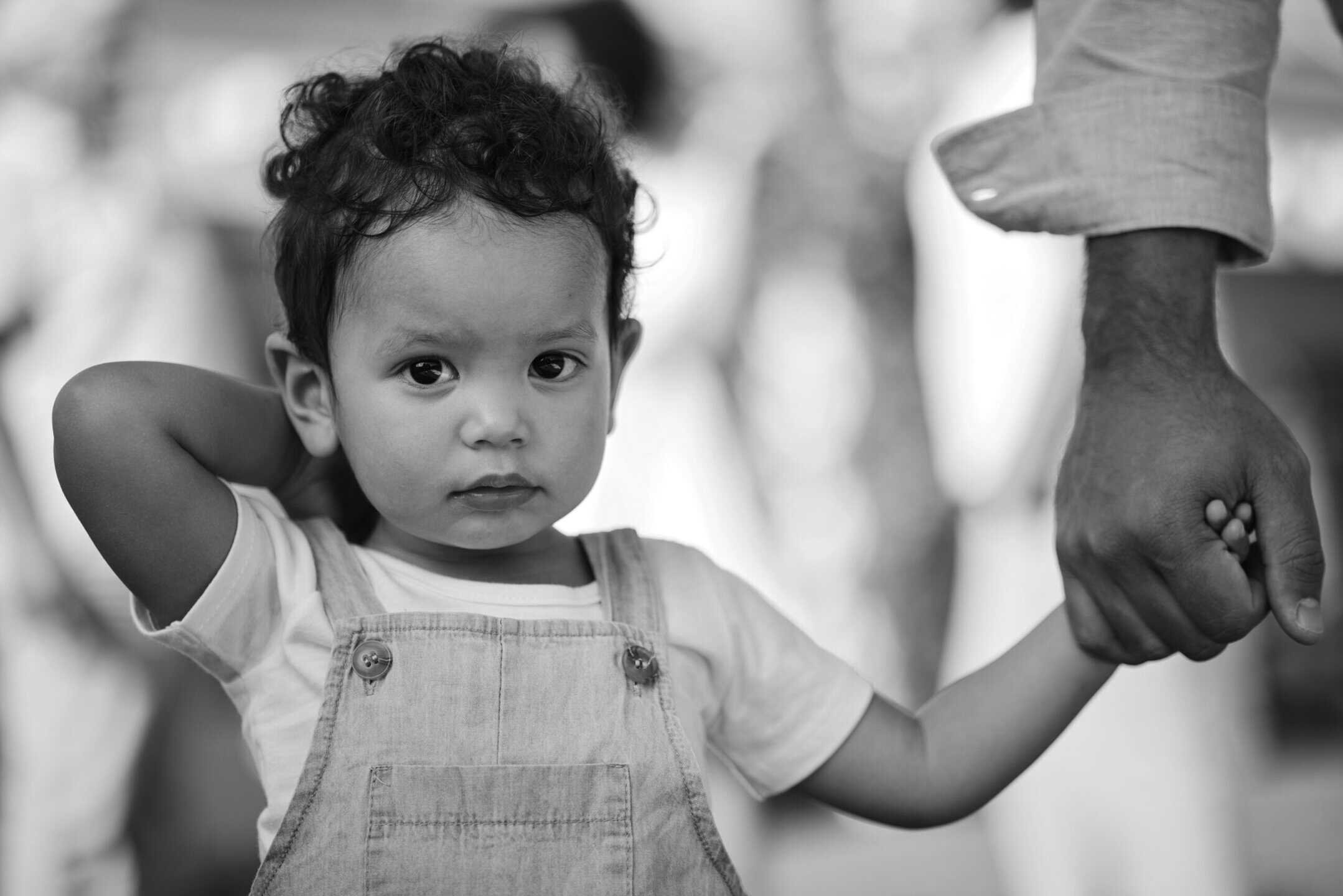 A toddler holding a caregiver's hand